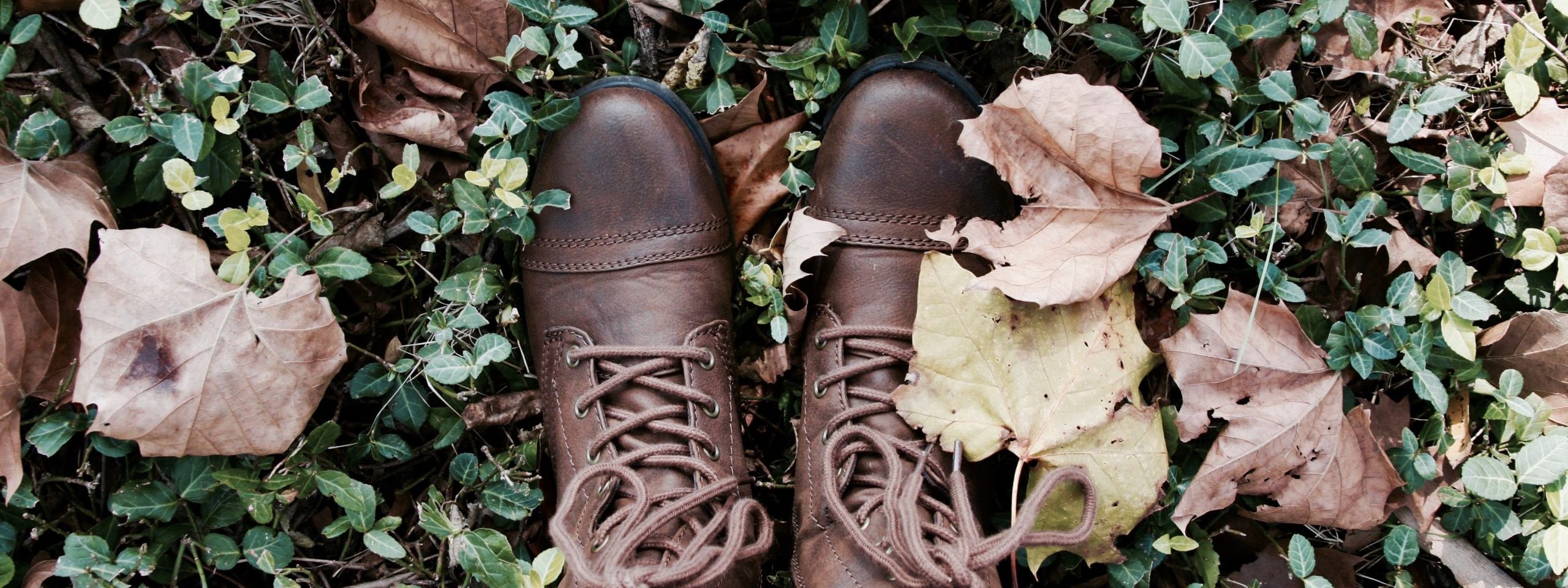 feet in fall leaves wearing brown boots