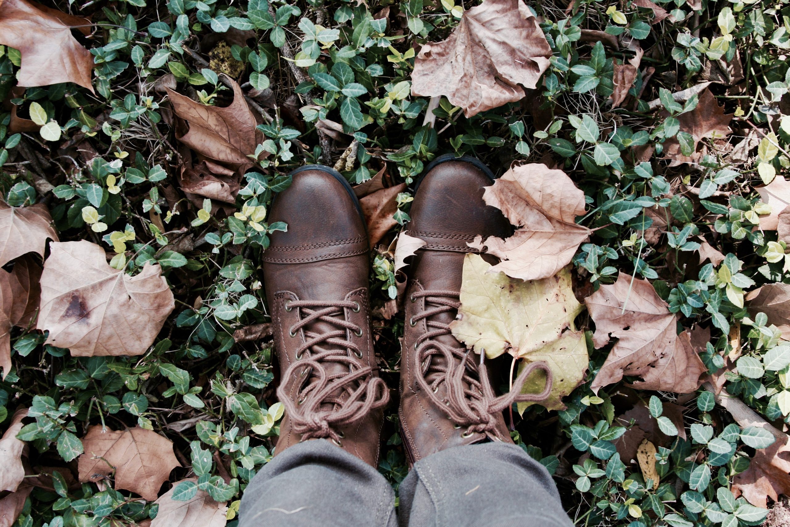 feet in fall leaves wearing brown boots